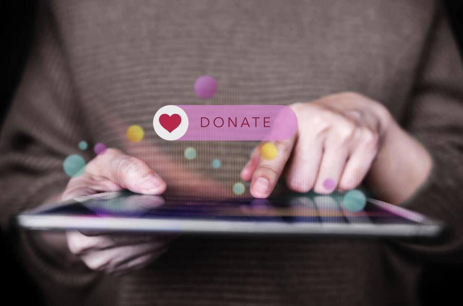 Main tenant une tablette avec une icône de don en surimpression